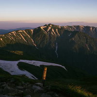 夜明けの飯豊本山から望む日本百名山の北部山々と残雪の写真