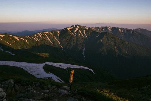 夜明けの飯豊本山から望む日本百名山の北部山々と残雪