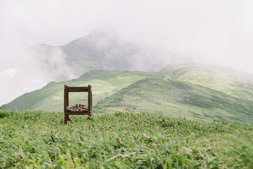 霧に包まれるギルダ原の木製ベンチと飯豊山