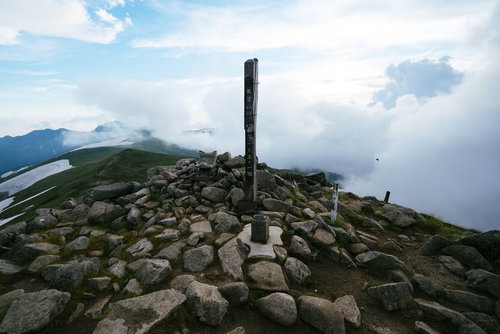 日本百名山・飯豊山の山頂標識と雲海、遠景の山々