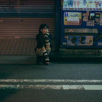 待ち合わせ時間にひとりきり、シャッターの前で待つ女性の写真