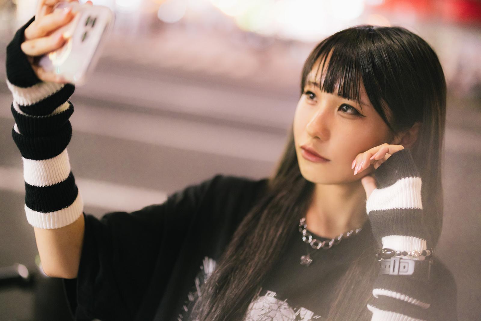スマホで自撮りする、ボーダー柄の服を着た長髪の女性［モデル：るい］