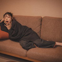 ソファーの上であくびをする寝落ち間際の女性の写真