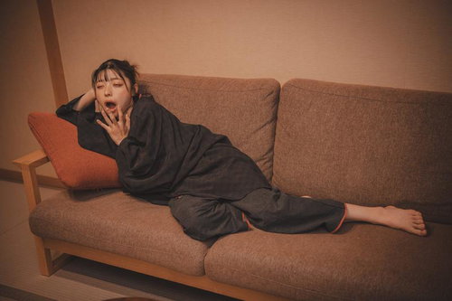 ソファーの上であくびをする寝落ち間際の女性