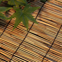 竹製のすだれの上に置かれた楓の葉と夏の涼しさの写真
