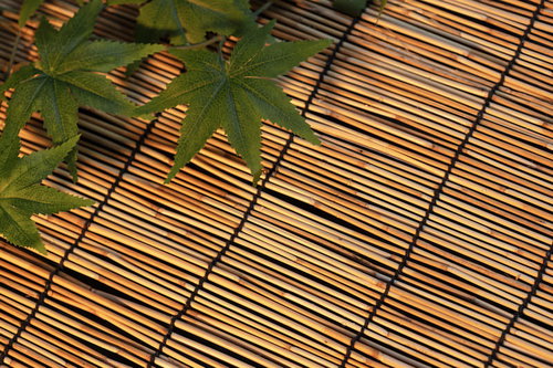 竹製のすだれの上に置かれた楓の葉と夏の涼しさ