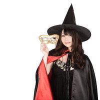 仮装用マスクを外した魔女が金色のベネチアンマスクを持つハロウィンの写真