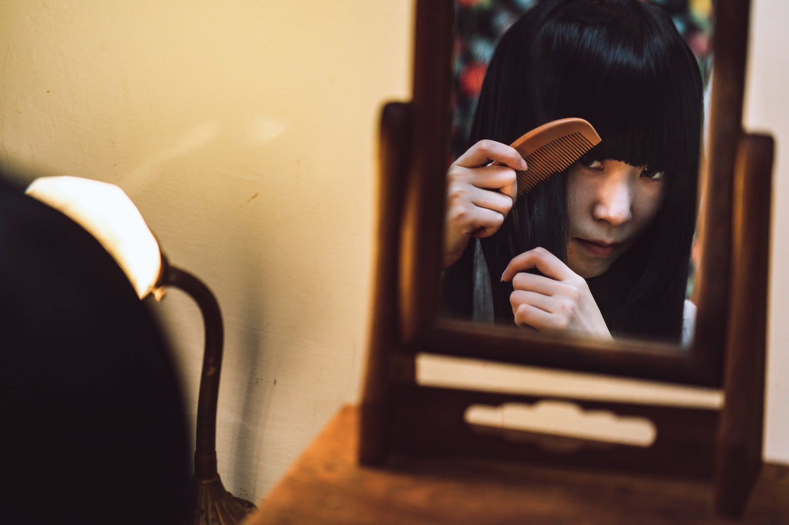 化粧台の鏡で髪に櫛を通している女性の不気味な写真［モデル：緋真煉］