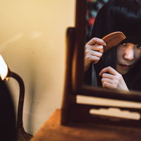 化粧台の小さな鏡で髪に櫛を通す女性の不気味な姿の写真