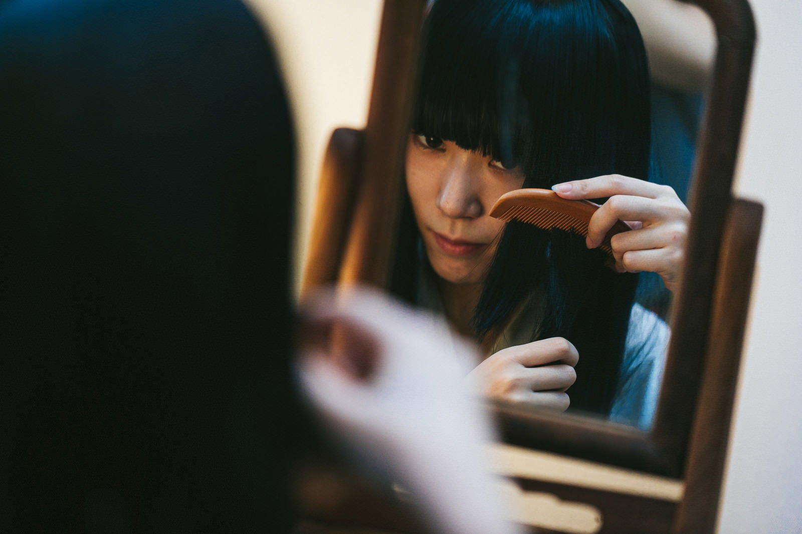 古民家の室内で手鏡を見ながら櫛で髪をとかす黒髪の女性［モデル：緋真煉］