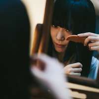 古民家の室内で鏡を見ながら髪をとかす日本女性の写真