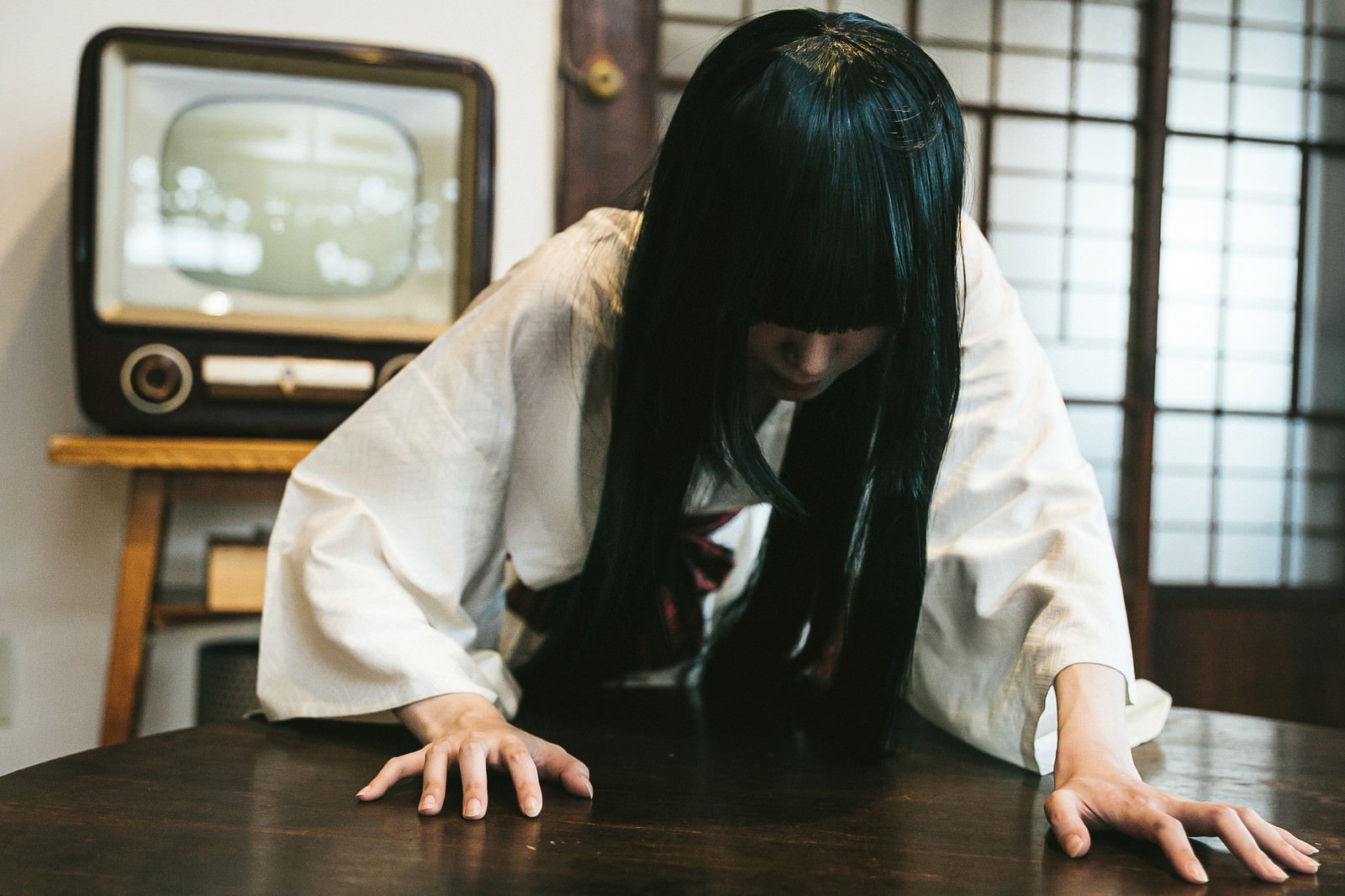 古いモニターを背に畳の上で這いつくばる長い黒髪の女性［モデル：緋真煉］