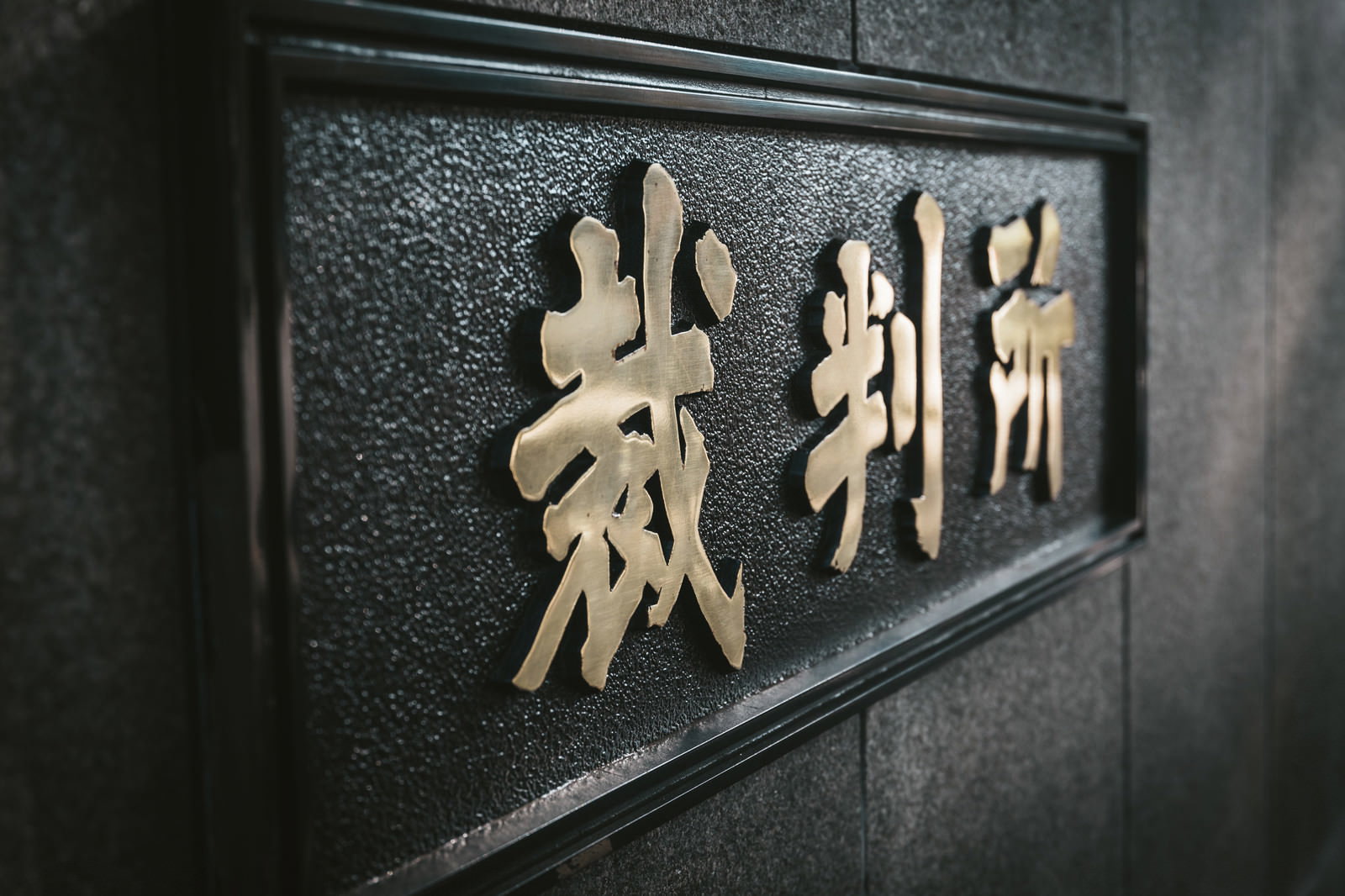 石の壁面に金色の文字で「裁判所」と刻まれた高等裁判所の看板