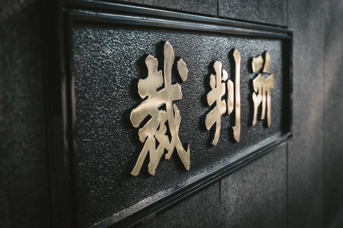 高等裁判所前の金色看板と石造り建築、司法機関の権威を象徴する厳粛な景観