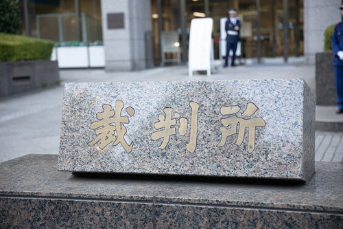 裁判所の入り口を警備する制服姿の警備員と石製看板