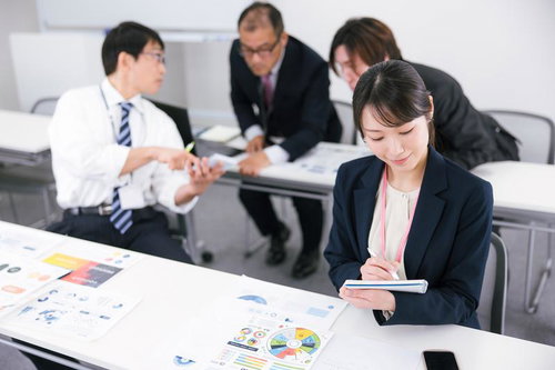 打ち合わせ中に会議室の資料に目を落とすビジネスウーマン