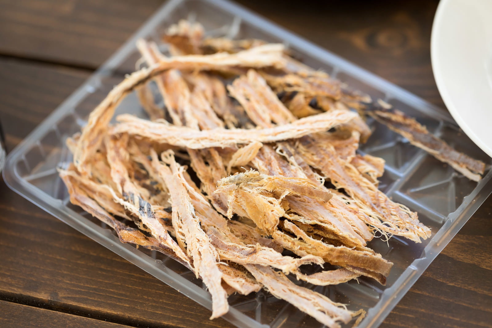 Dried squid snack arranged on a transparent plate