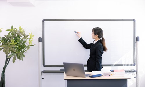 ホワイトボードに書いて説明する女性講師の研修風景