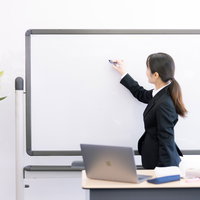 ホワイトボードに書き込みながら説明する女性講師の写真