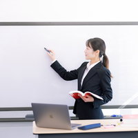 ホワイトボードに要点をまとめて説明する女性講師の写真