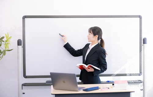 ホワイトボードに要点をまとめて説明する女性講師