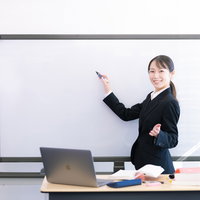 黒いスーツを着た笑顔でプレゼンテーションをする女性の写真