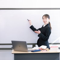 笑顔で授業をする女性講師がホワイトボードで説明しているの写真