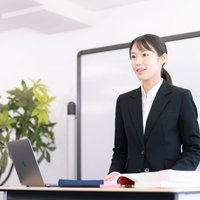 登壇して指導する女性講師の講演会でのプレゼンテーションの写真