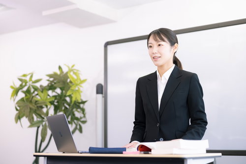登壇して指導する女性講師の講演会でのプレゼンテーション