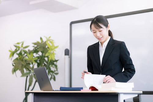 ホワイトボードの前で資料を説明する新人研修の女性講師