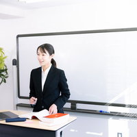 ホワイトボードの前でプレゼンする女性社員の写真