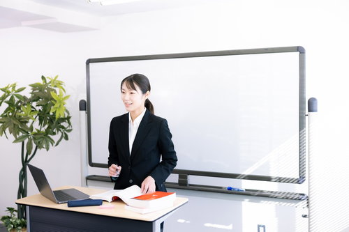 ホワイトボードの前でプレゼンする女性社員