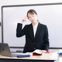 悩みこむ登壇する女性講師、頭痛に苦しむ表情の写真