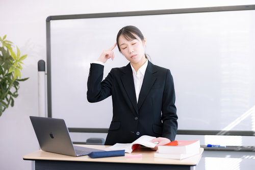 悩みこむ登壇する女性講師、頭痛に苦しむ表情
