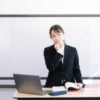 登壇中にホワイトボードの前で戸惑う女性講師の写真