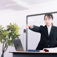 授業中に注意する女性講師が指をさして指摘しているの写真