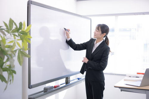 ホワイトボードで商品説明する女性講師のセミナー・研修風景