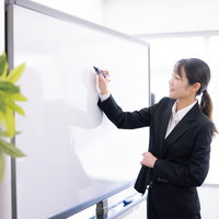 ホワイトボードに書き込む女性講師の講義風景の写真