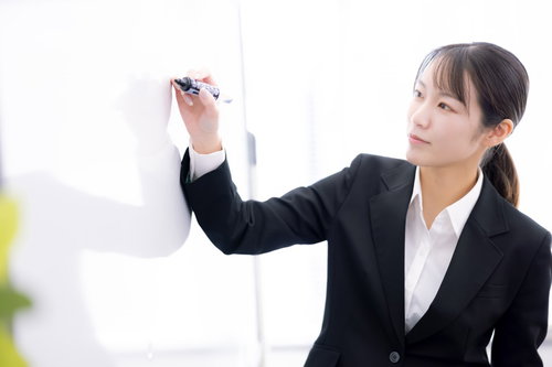 ホワイトボードに書いて説明する女性社員のプレゼンテーション