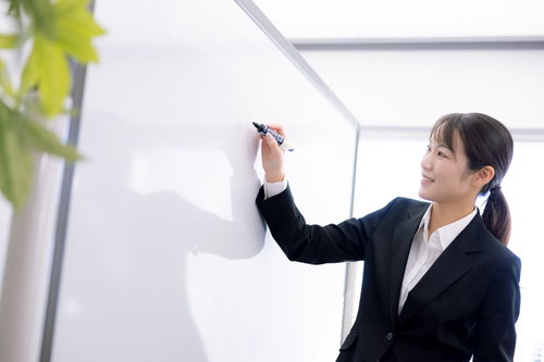 笑顔で説明を続ける女性講師がホワイトボードの前でプレゼン