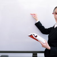 何度も説明をするホワイトボード前の女性講師の写真