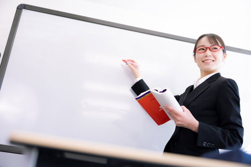 ホワイトボードの前で笑顔で質問に回答する女性講師