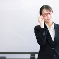 赤い眼鏡をかけた女性講師がセミナーで説明する姿の写真
