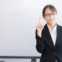 ナンバーワンを強調する人差し指を立てる女性講師の写真