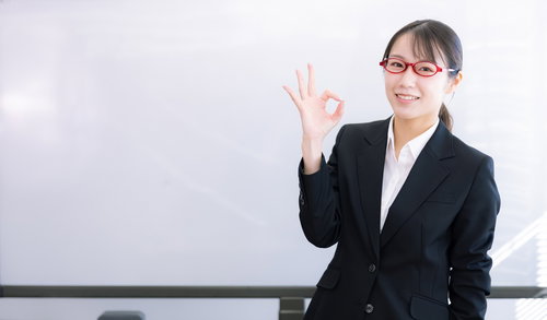 OKサインをする黒いスーツの赤い若い女性講師