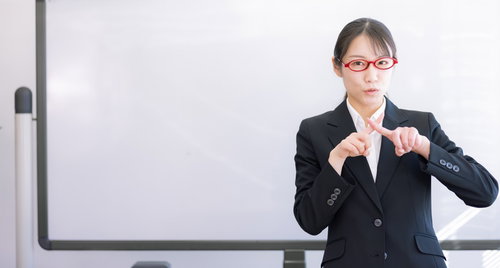 不合格のバツサインを出す女性講師の厳しい指導