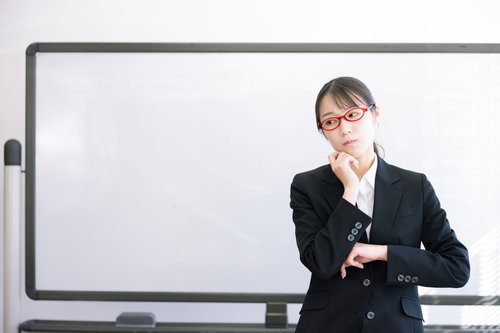 疑問に思う赤い眼鏡をかけた女性講師がセミナーで考える様子
