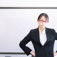 ホワイトボード前でご立腹の女性講師がセミナーで厳しく指導している場面の写真