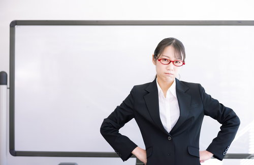 ホワイトボード前でご立腹の女性講師がセミナーで厳しく指導している場面
