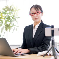 スマートフォンで動画配信をおこなうオンライン授業の女性講師の写真